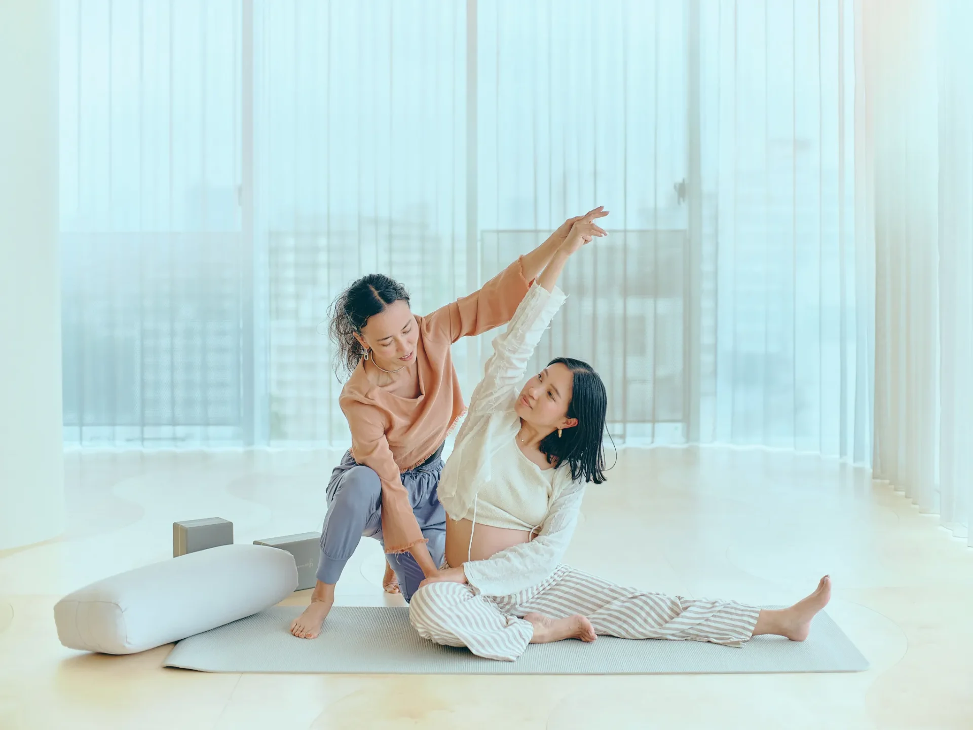 妊婦さんのポーズをサポートする女性インストラクター